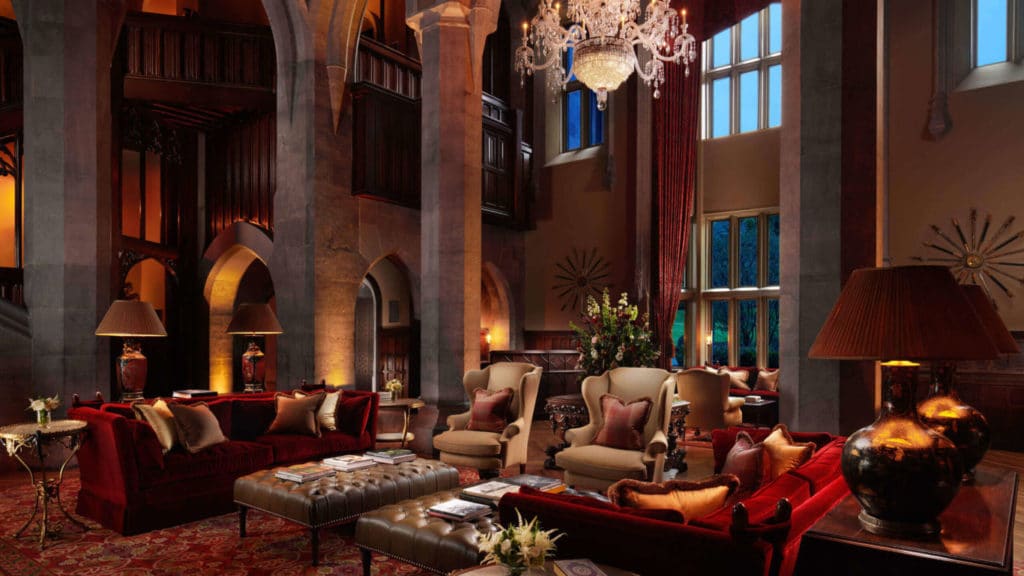 You can see the lush interiors of Adare Manor in this photograph. There's a chandelier, two beautiful pillar arches, and long windows with some gorgeous furnishings. 