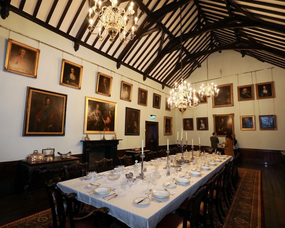 A photograph that shows the Great Hall at Malahide Castle in its full glory. You see its roof, the portraits adorning the walls, the banquet table laid out with candle stands and crystal ware - it reflects the serving style of the Talbots in the 1820s