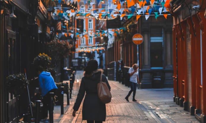 A woman walks in the evening time, the street has festive decorations, buntings put up - you can see that it is all festive looking in Ireland