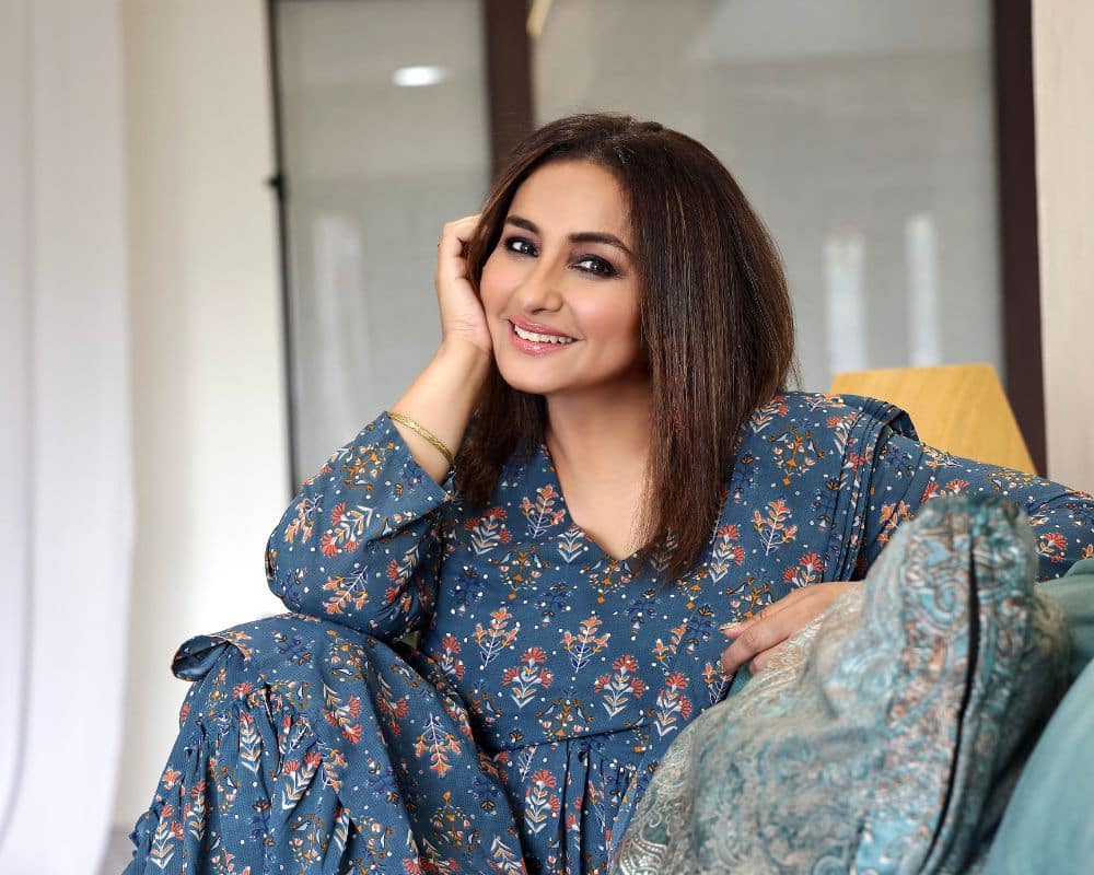 In the photograph, the actress Divya Dutta poses for the camera in a blue Indian dress which has flower motifs and her hair is left open, with a hand placed on her face. She smiles for this photograph, taken for the Indian Film Festival to be held in Ireland. 