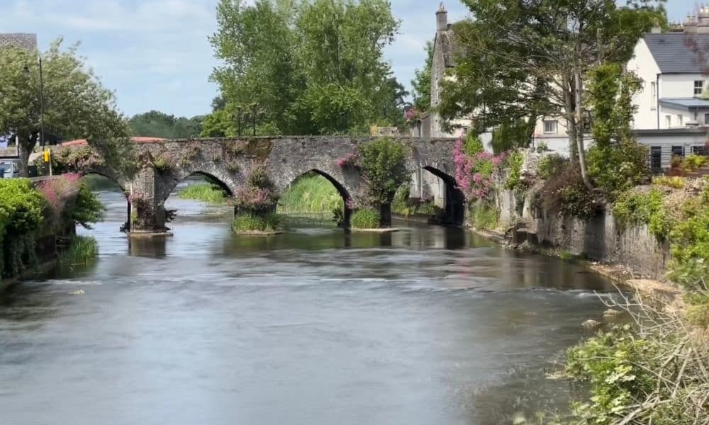 The oldest bridge in the tidiest town of Ireland - you see four arches, water, and green trees 