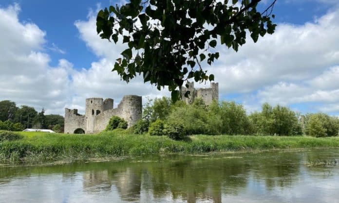 Historic Trim castle is seen in the picture, and a canopy of leaves in the foreground and the river waters and the reflection of the castle in Ireland's tidiest towns