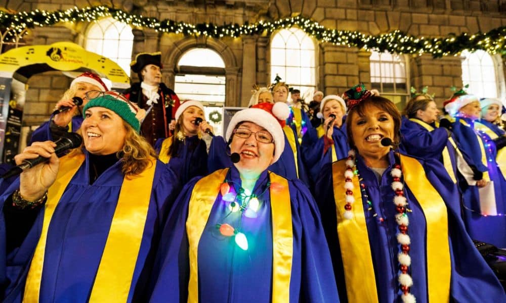 Various women in blue and yellow colour outfits singing at The Busk event and also singing at the carol event