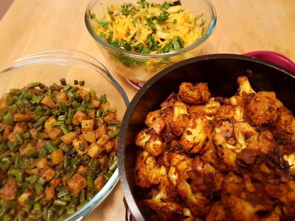 Cauliflower fry, and two other Indian dishes laid out on the table in separate bowls 