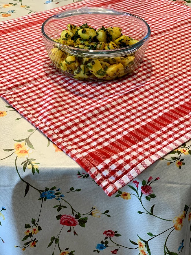 Potatoes and mint curry - placed in a bowl and the background has a red and white checks patterned cloth