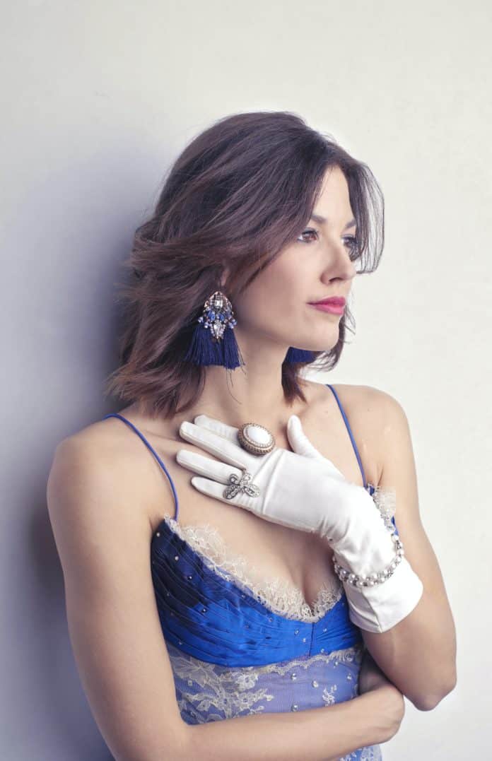 A woman in a deep neckline blue dress with gloves and ring - posing for a fashion shoot