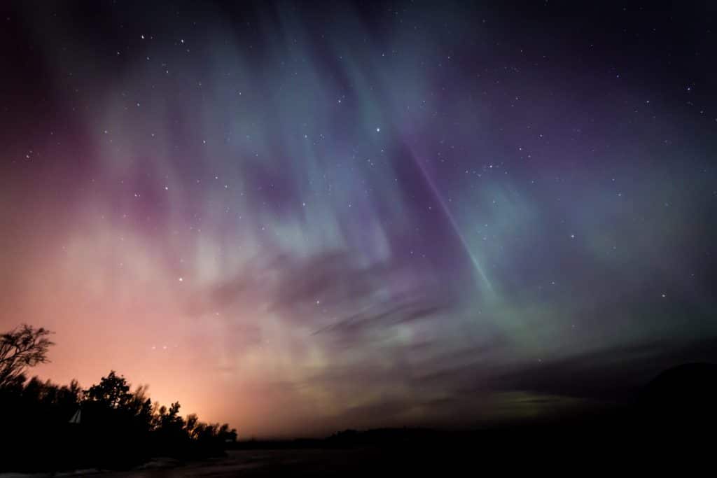 A sky lit up with Northern Lights in shades of purple, green and pink