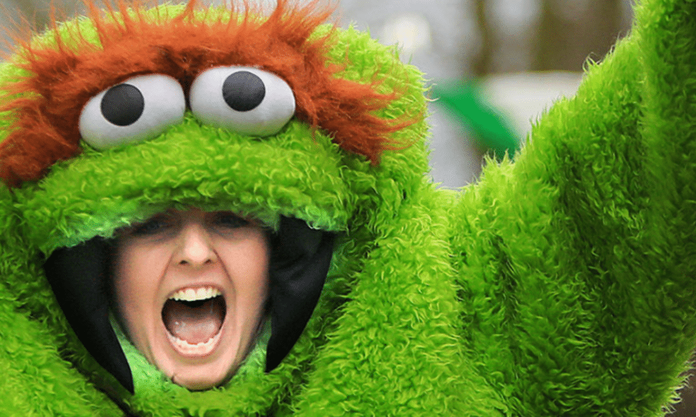 A woman in a green costume with beady eyes on top of her head