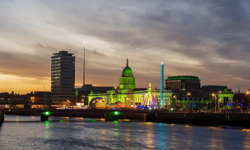 Iconic monuments in Dublin lit up in green for St. Patrick's Day and their colours reflected in Liffey river